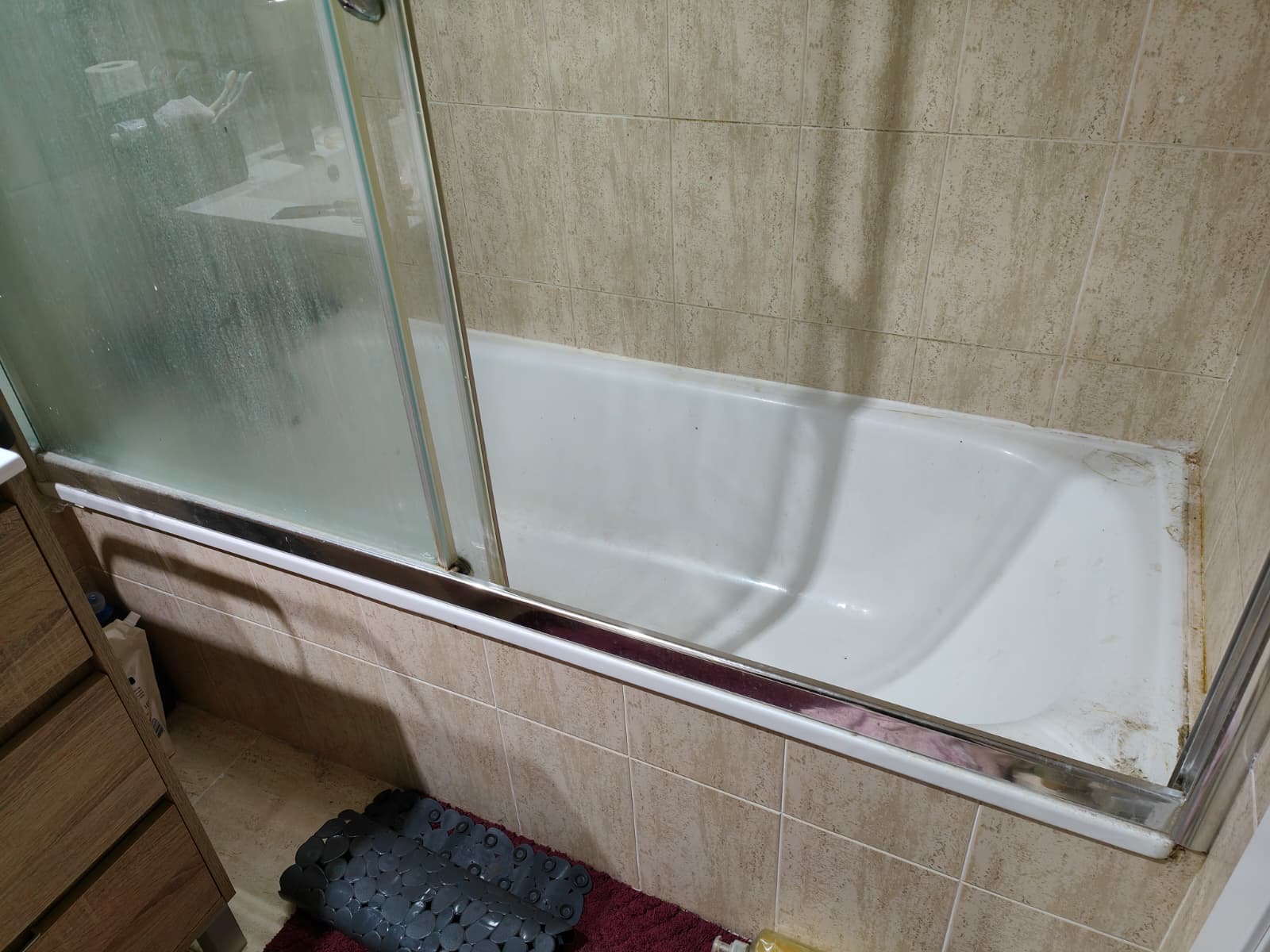 La bañera original con la mampara corredera y las juntas deterioradas