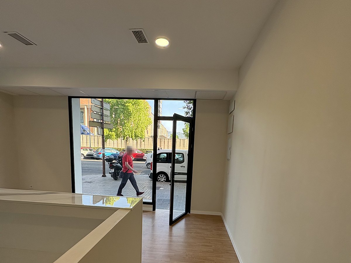 Acceso y escaparate del despacho tras la reforma, con carpintería negra y suelo de madera